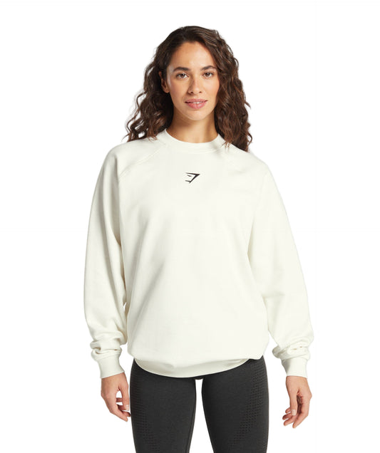 Woman wearing a white sweatshirt with a logo on a light gray background
