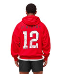 Person wearing a red hoodie with 'GYMSHARK' and number '12' on the back, standing against a beige background.